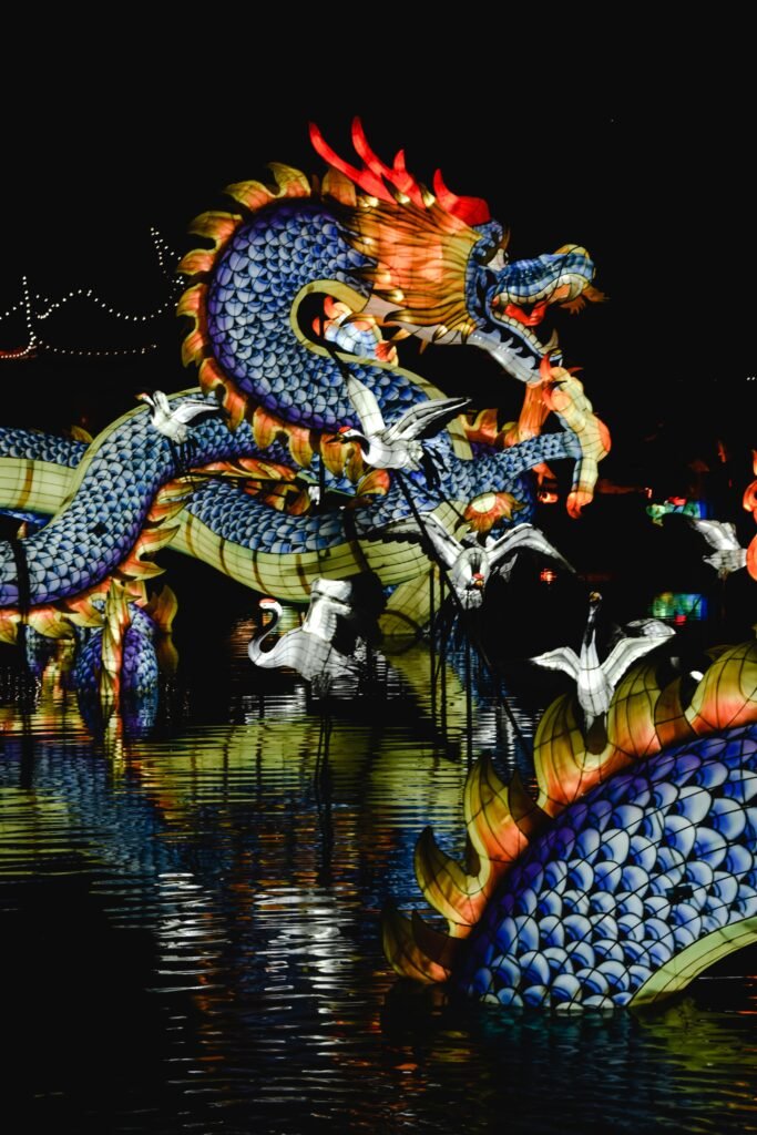 Vibrant dragon lantern installation reflecting over water at night festival.